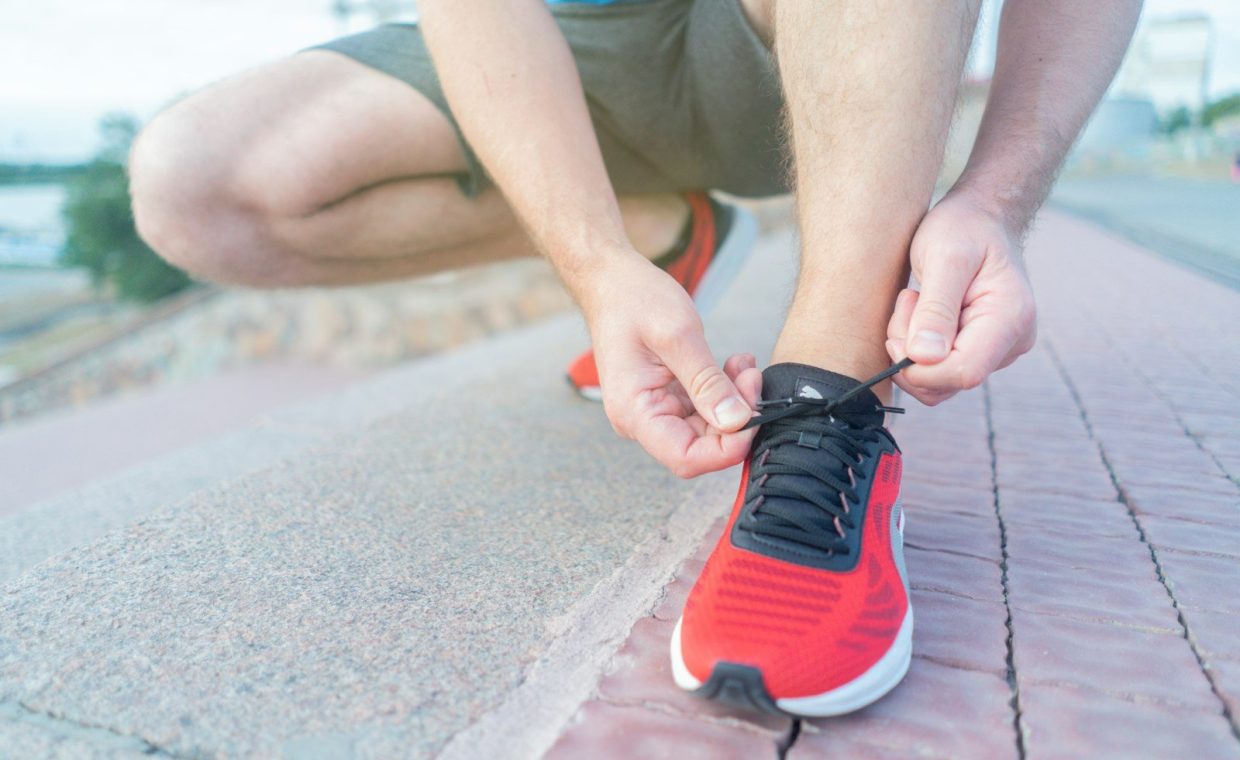 person in red nike sneakers sitting on concrete floor