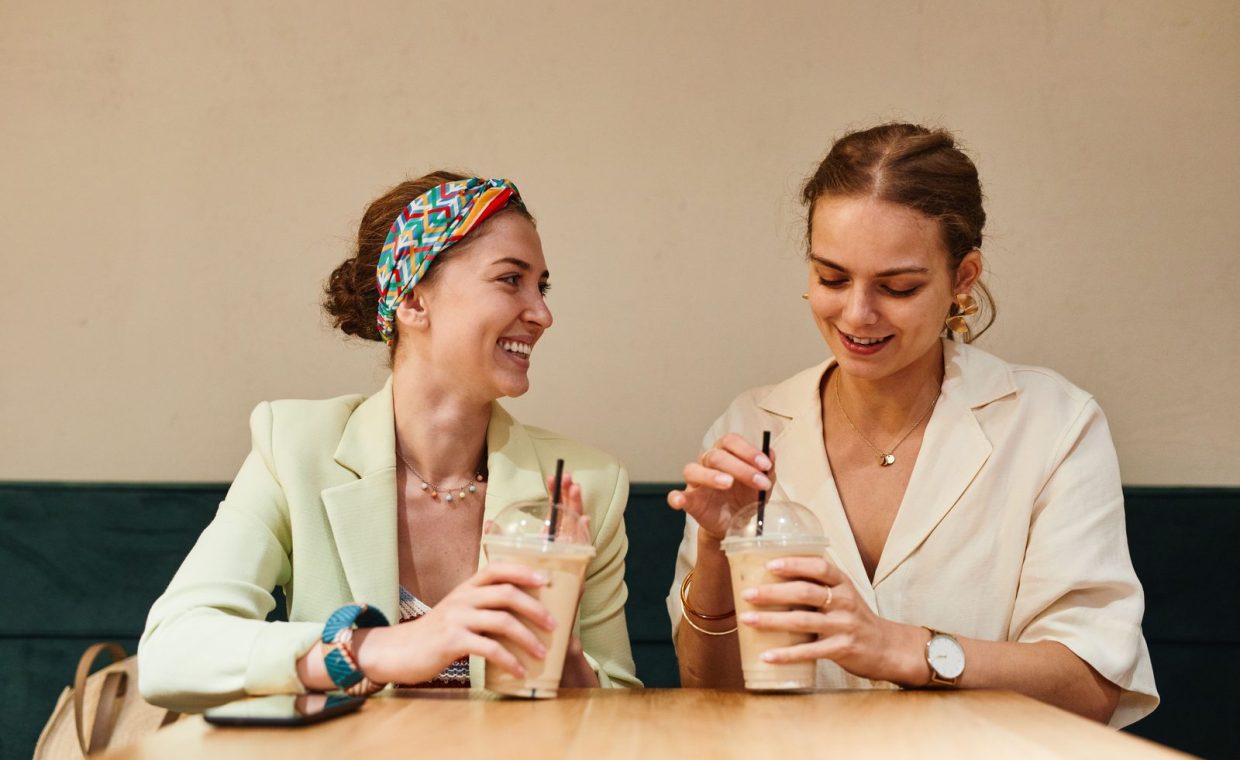 Two young women having a lively conversation over iced coffee at a café.
