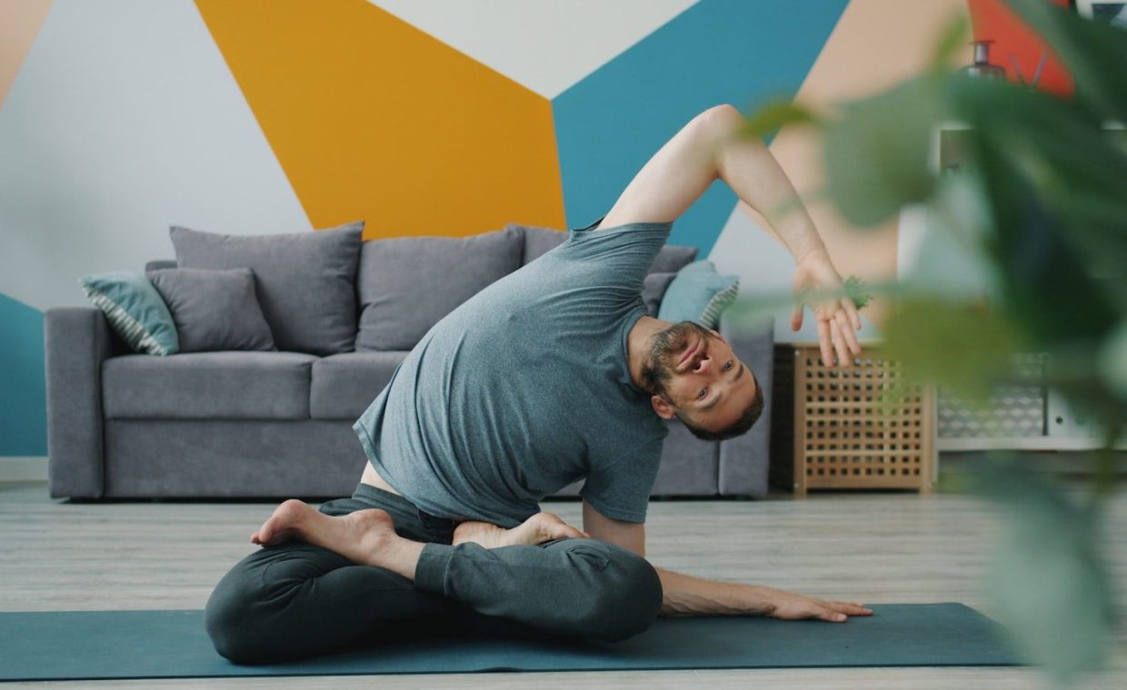 Man in yoga pose on mat in living room