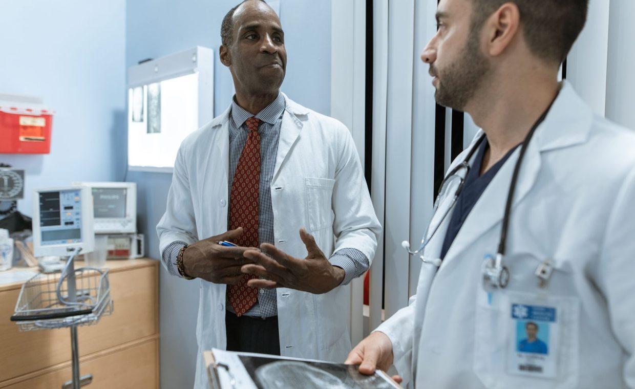 Two doctors in lab coats discussing an X-ray in a clinical setting.