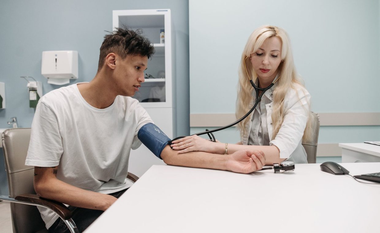 A doctor measures a patient's blood pressure in a clinic setting, focusing on healthcare and wellness.