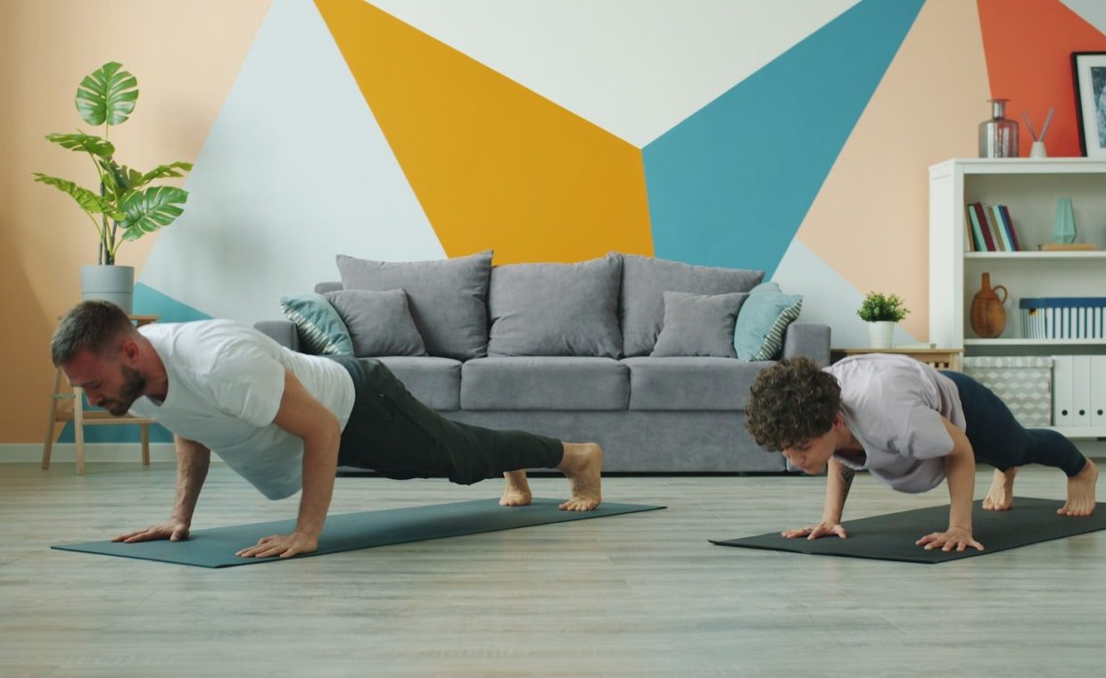 Man and woman doing push-ups on yoga mats.