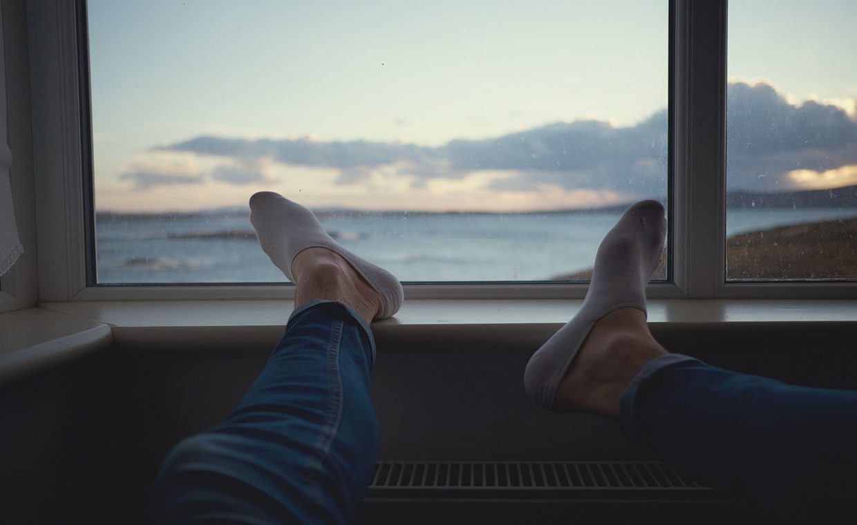 Scene of person relaxing by a window, enjoying a serene ocean view.