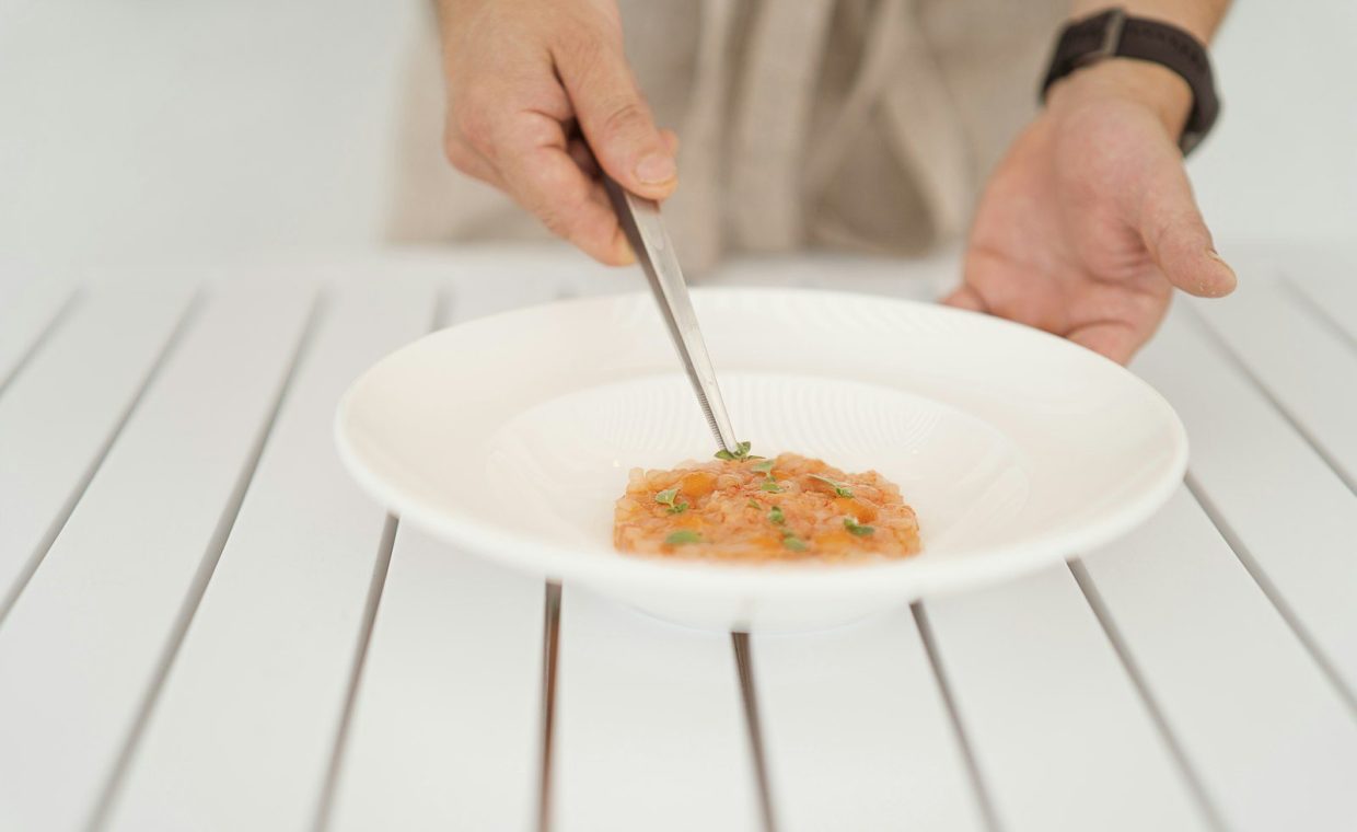 A person cutting food on a white plate