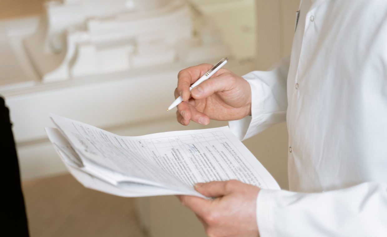 A doctor holds and reviews medical documents, demonstrating careful examination and professionalism.