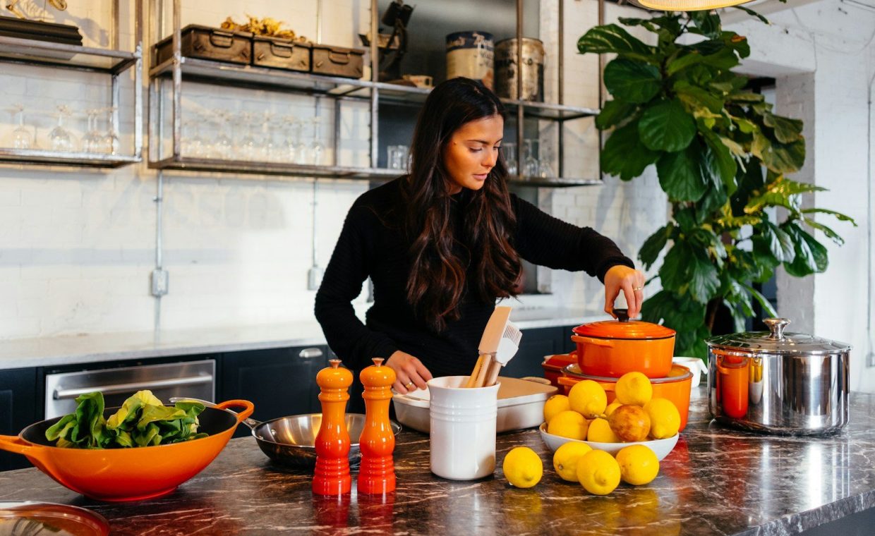 woman standing in front of fruits holding pot's lid