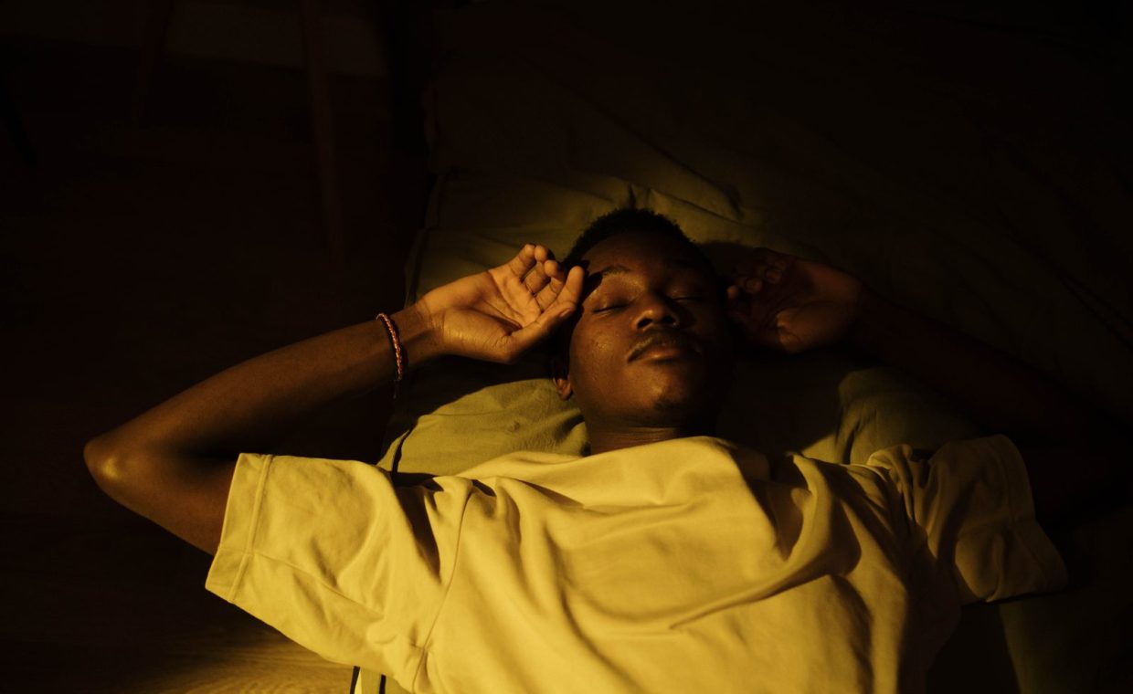 A man lying down in a cozy, warm-lit room, peacefully asleep during the night.