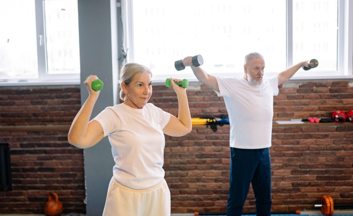 Elderly man and woman workout with dumbbells promoting healthy lifestyle and fitness.