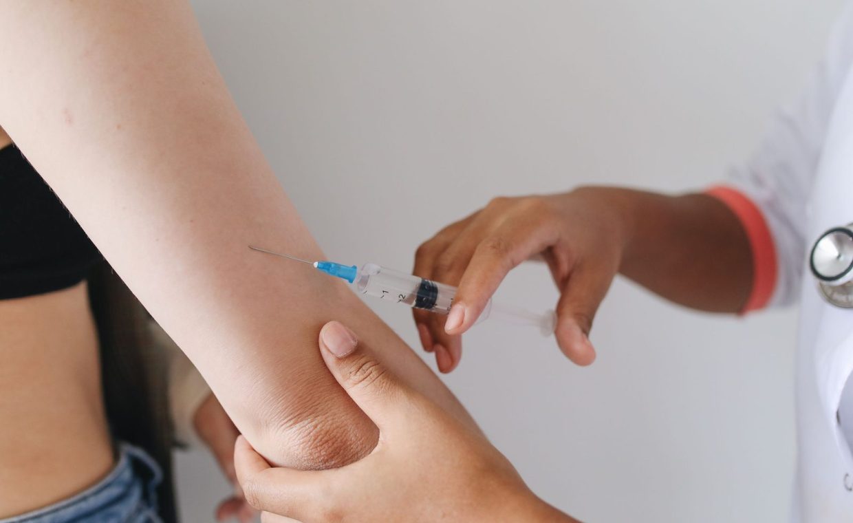 Doctor administering an injection to a patient's arm, close-up view.