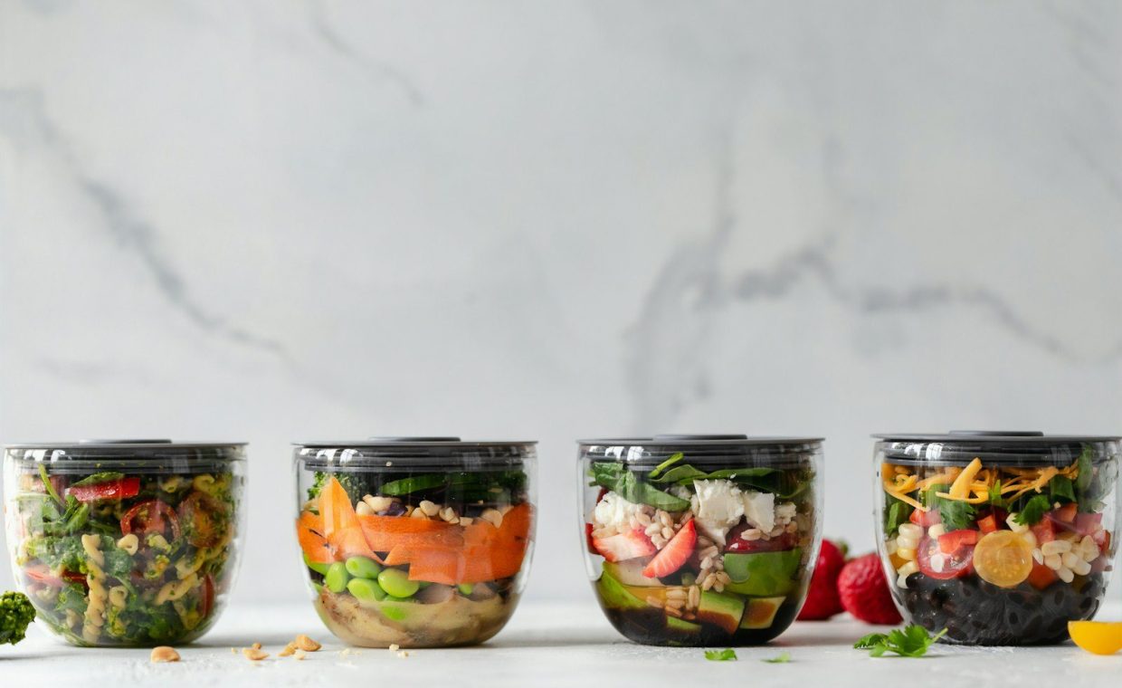 four clear plastic bowls with vegetables
