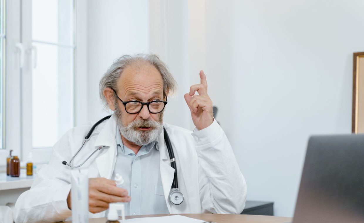 Senior doctor in white coat having an online consultation. Medical professional using technology for healthcare.